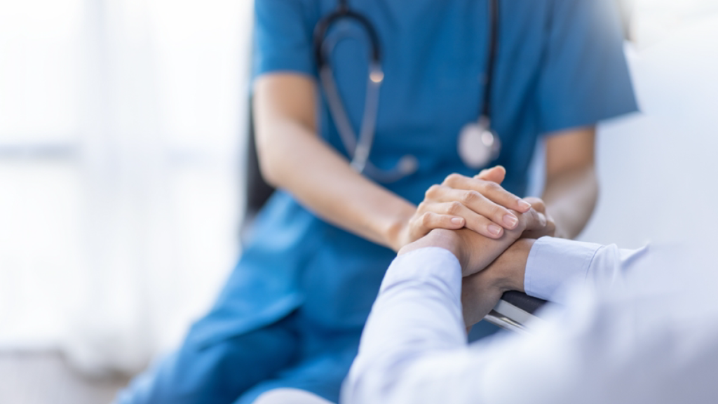 Healthcare professional holding patient’s hand—symbolizing compassion and the impact of effective healthcare staff training.